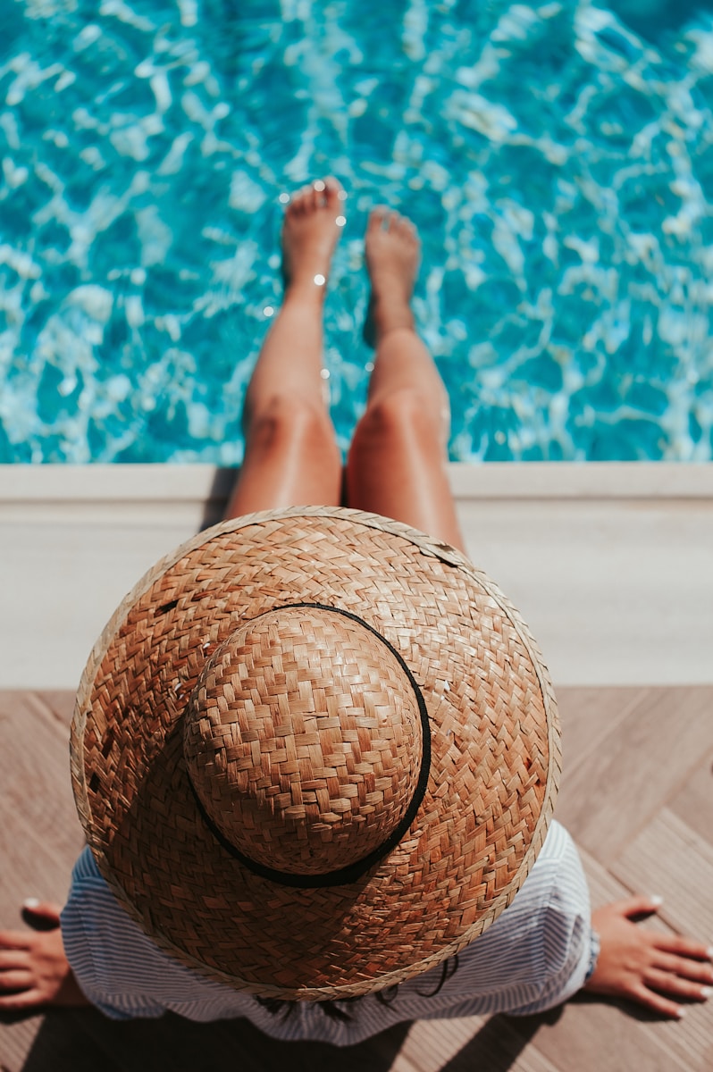Photo by Angelo Pantazis woman sitting on poolside setting both of her feet on pool