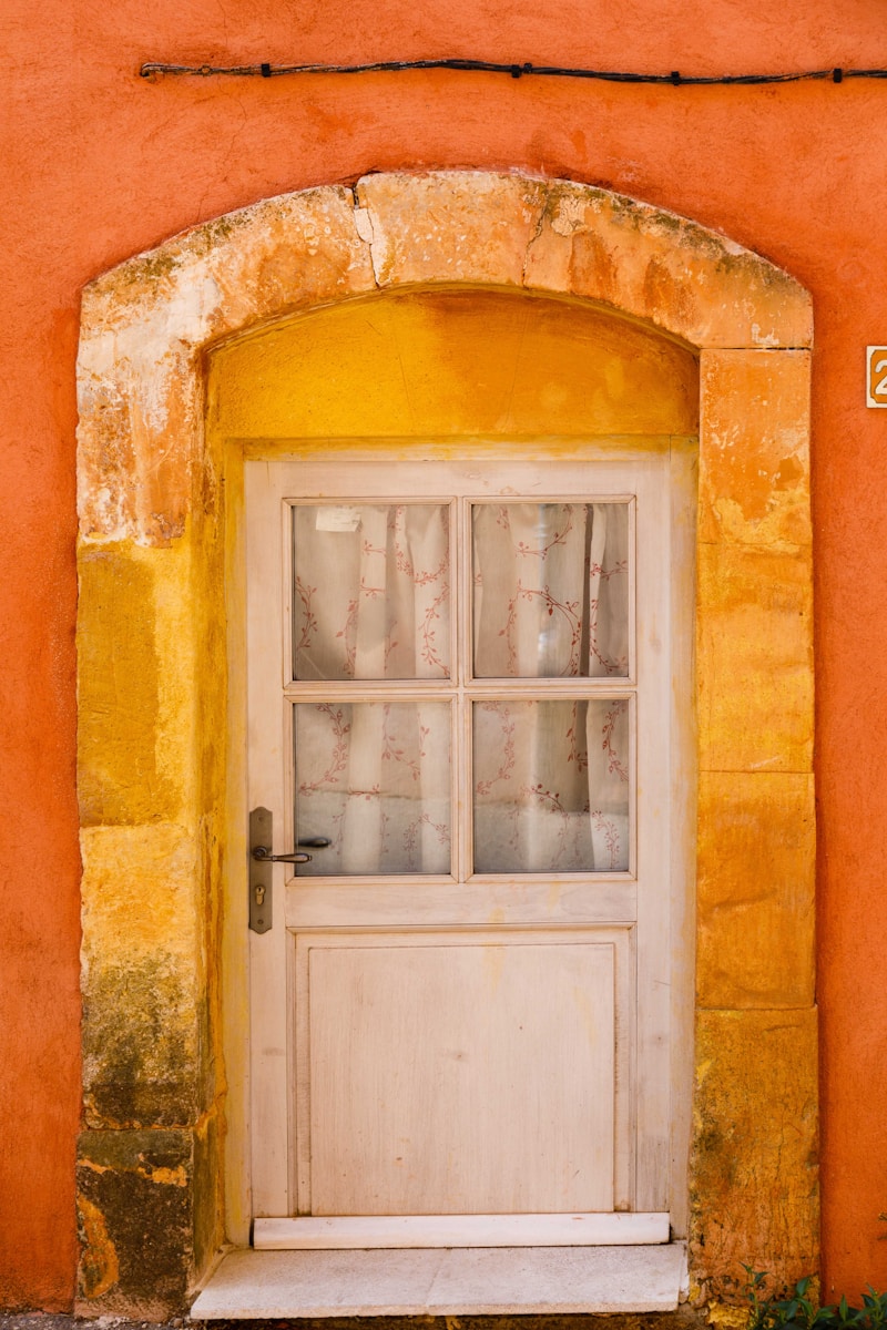 Photo by Henri Picot a white door with a window on a yellow wall